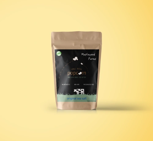A kraft popcorn bag with a black and green Maplewood Farms label on a pale yellow background